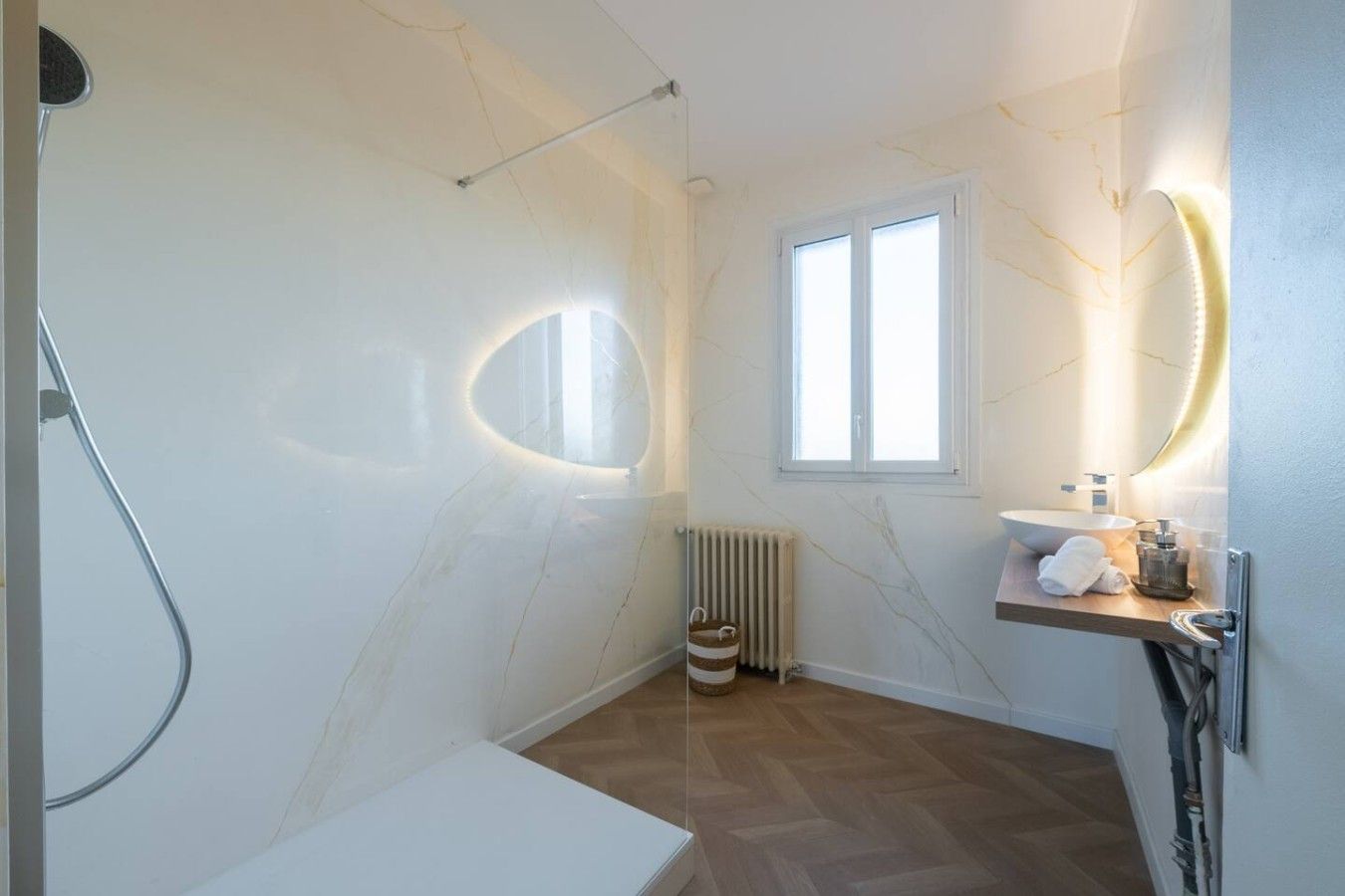 Een badkamer met een douche, toilet, wastafel en raam.