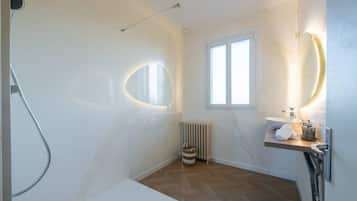 Een badkamer met een douche, toilet, wastafel en raam.