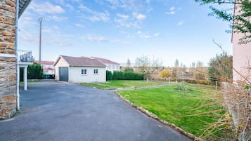 A residential driveway leading to a house with a garage, a well-maintained lawn, and a clear sky.