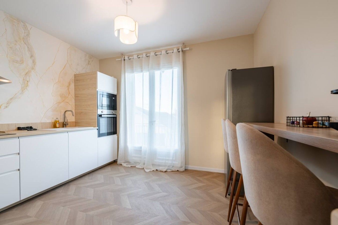 Een moderne keuken met een inbouwoven, een koelkast en een eethoek met een stoel.