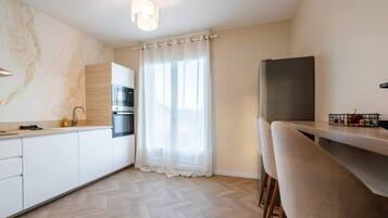 Een moderne keuken met een inbouwoven, een koelkast en een eethoek met een stoel.