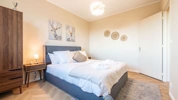 Ein Schlafzimmer mit einem Bett, Nachttischen, einem Kleiderschrank, Bildern an der Wand und einer Tür.