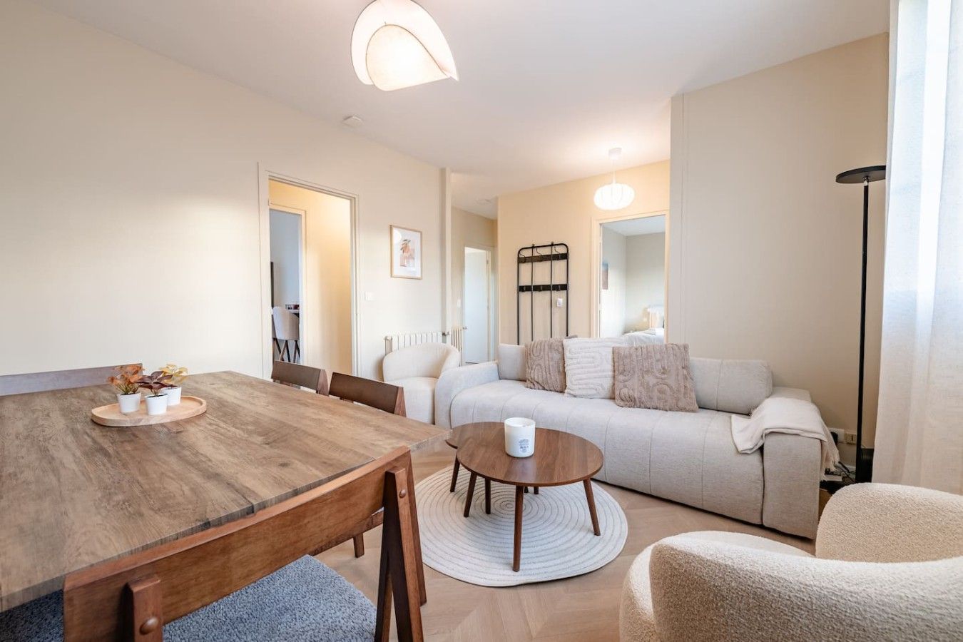 Een moderne woonkamer met een houten eettafel, een ronde salontafel, een bank en een vloerlamp.