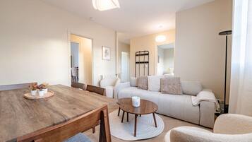 Een moderne woonkamer met een houten eettafel, een ronde salontafel, een bank en een vloerlamp.