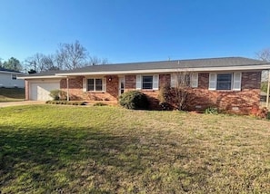 A two-story brick house with a front garage, a well-maintained lawn, and a clear blue sky. - Your Home Base for OSU Game Days & Stillwater Stays (Stillwater)
