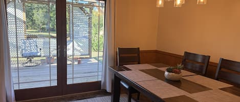 A dining area with a table set for four, a sliding glass door leading to an outdoor patio, and a hanging light fixture.