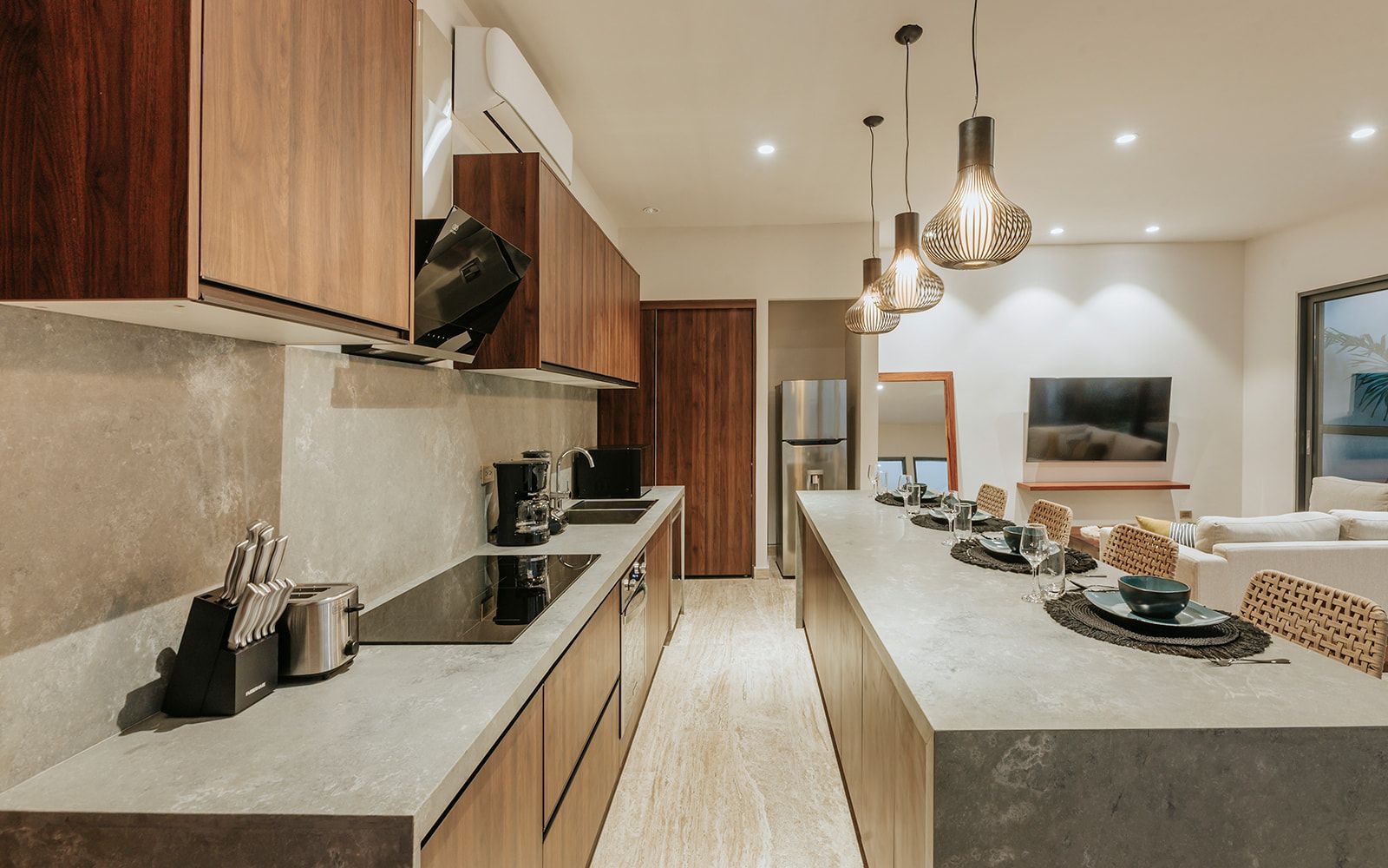 Een moderne keuken met een centraal eiland, houten kastjes en een eethoek met een televisie.
