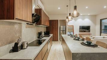 Een moderne keuken met een centraal eiland, houten kastjes en een eethoek met een televisie.