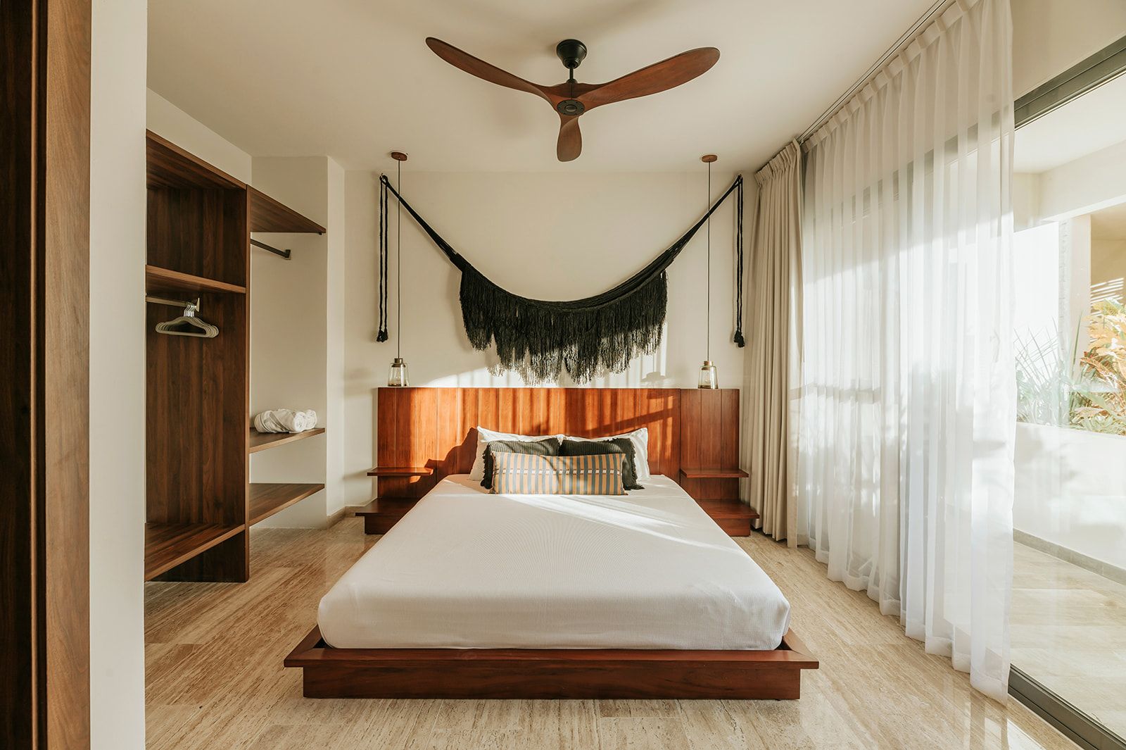 Una camera da letto moderna con un letto con struttura in legno, una ventola a soffitto e un'ampia finestra con tende leggere.