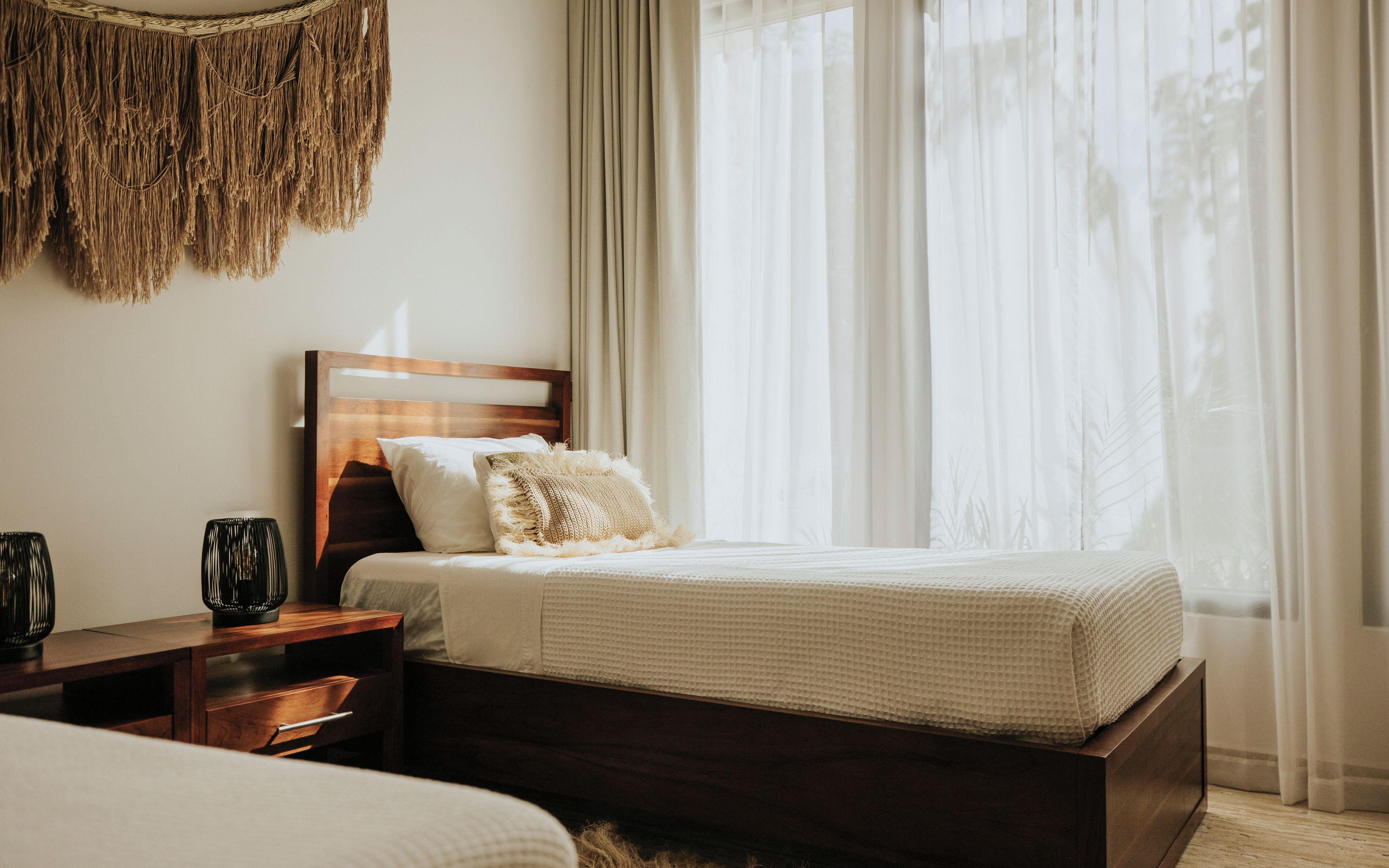 Una camera da letto con un letto, comodini e una finestra con tende.