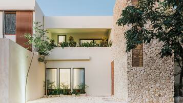 Een modern gebouw met een stenen gevel, een plat dak en een balkon met beplanting.
