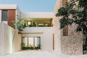 Ein modernes Gebäude mit einer Stein-Fassade, einem flachen Dach und einem Balkon mit Pflanzen.