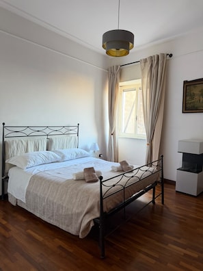 A bedroom with a bed, a bedside table, a hanging light fixture, and a window with curtains. - Apartment 500 m from the beaches and the harbor (Castellammare di Stabia)