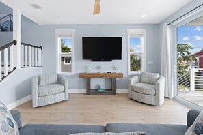 A modern living room with a flat-screen TV, two armchairs, a sofa, and a wooden coffee table. - 🐢The Turtle Nest | Private Heated Pool | Newly Built Home (Fort Myers beach)