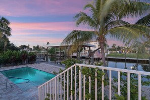 A swimming pool with a view of a waterfront and a building in the background. - 🌴Oasis on Ohio Ave | Canal-Front | Private Heated Pool + Steps to Beach 🌴 (Fort Myers Beach)