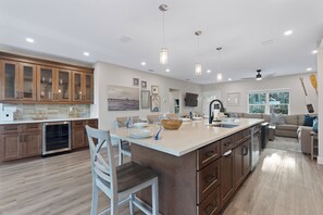 A spacious kitchen with a large island, wooden cabinets, and a dining area with chairs and a table. - 🌴Oasis on Ohio Ave | Canal-Front | Private Heated Pool + Steps to Beach 🌴 (Fort Myers Beach)