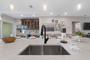 Een moderne keuken met een roestvrijstalen spoelbak, een houten kom en een glazen vaas.