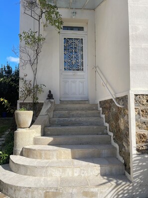 A white building with a decorative door and a set of stone steps leading to the entrance. - A bright and elegant home (Chartres)