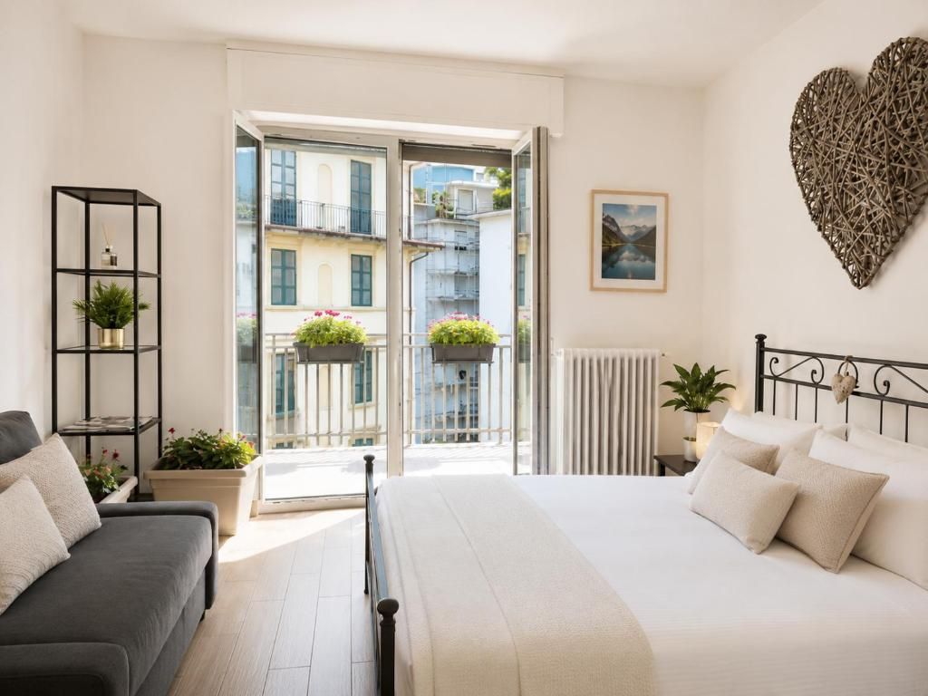 Une chambre avec un lit, un canapé, un balcon agrémenté de plantes et un élément de décoration murale en forme de cœur.