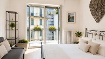 Une chambre avec un lit, un canapé, un balcon agrémenté de plantes et un élément de décoration murale en forme de cœur.