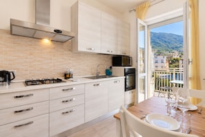 A modern kitchen with a gas stove, microwave, and oven, a sink, and a dining area with a table set for two.