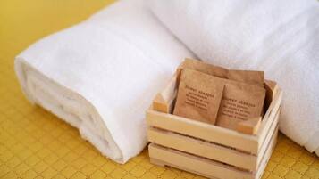 A stack of white towels and a wooden crate with two brown paper bags labeled 'Shower shampoo'.