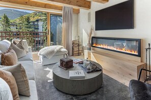 Un salon moderne avec une cheminée, un canapé, une table basse et une vue sur l’extérieur.