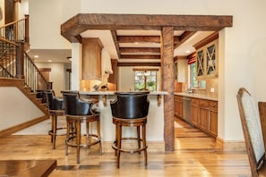 Una cocina con barra, suelo de madera y una escalera.