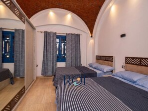 A hotel room with a brick ceiling, two beds with striped bedding, a wooden headboard, and a large mirror on one wall. - Sea View Villa with Pool at Amaros, Sahl Hasheesh (Red Sea Governorate)