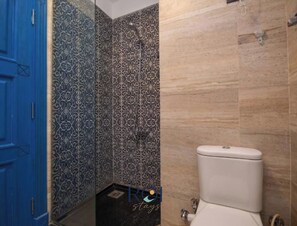 A bathroom with patterned tiles, a blue door, and a white toilet.