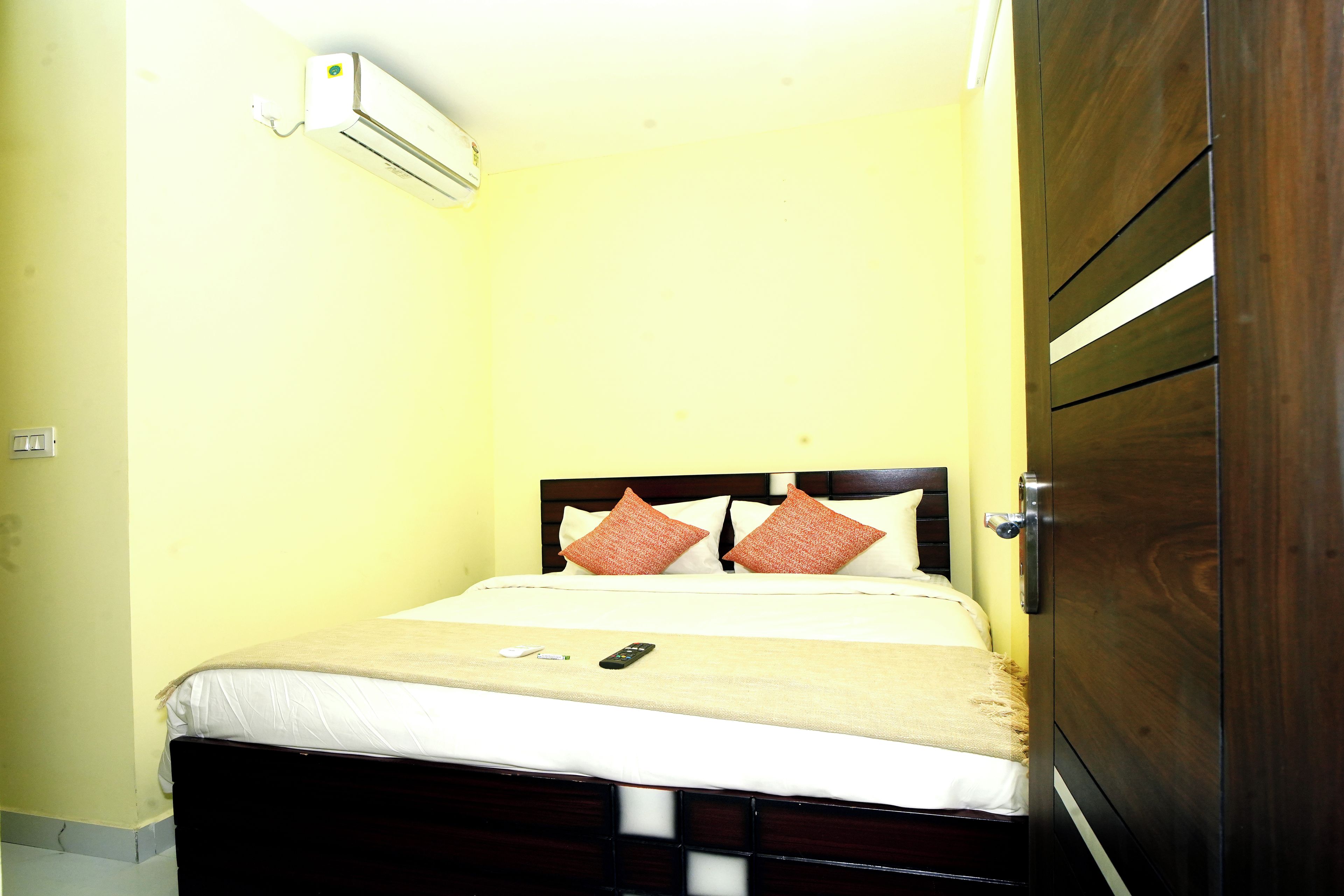 Una cama individual con cabecera de madera, una mesita de noche y un aire acondicionado instalado en la pared.