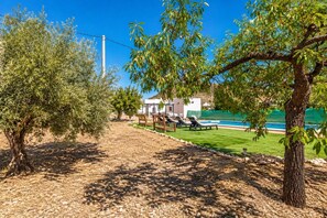 An outdoor area with a pool, lounge chairs, and a building in the background. - Villa Milano – 4 bedroom house with private pool & garden in Lubrin (La Rambla Aljibe)