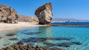 A coastal landscape with clear turquoise waters, rocky formations, and distant buildings. - Villa Milano – 4 bedroom house with private pool & garden in Lubrin (La Rambla Aljibe)