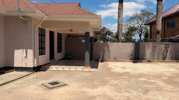 A residential property with a covered porch, a concrete driveway, and a tall palm tree in the background.
