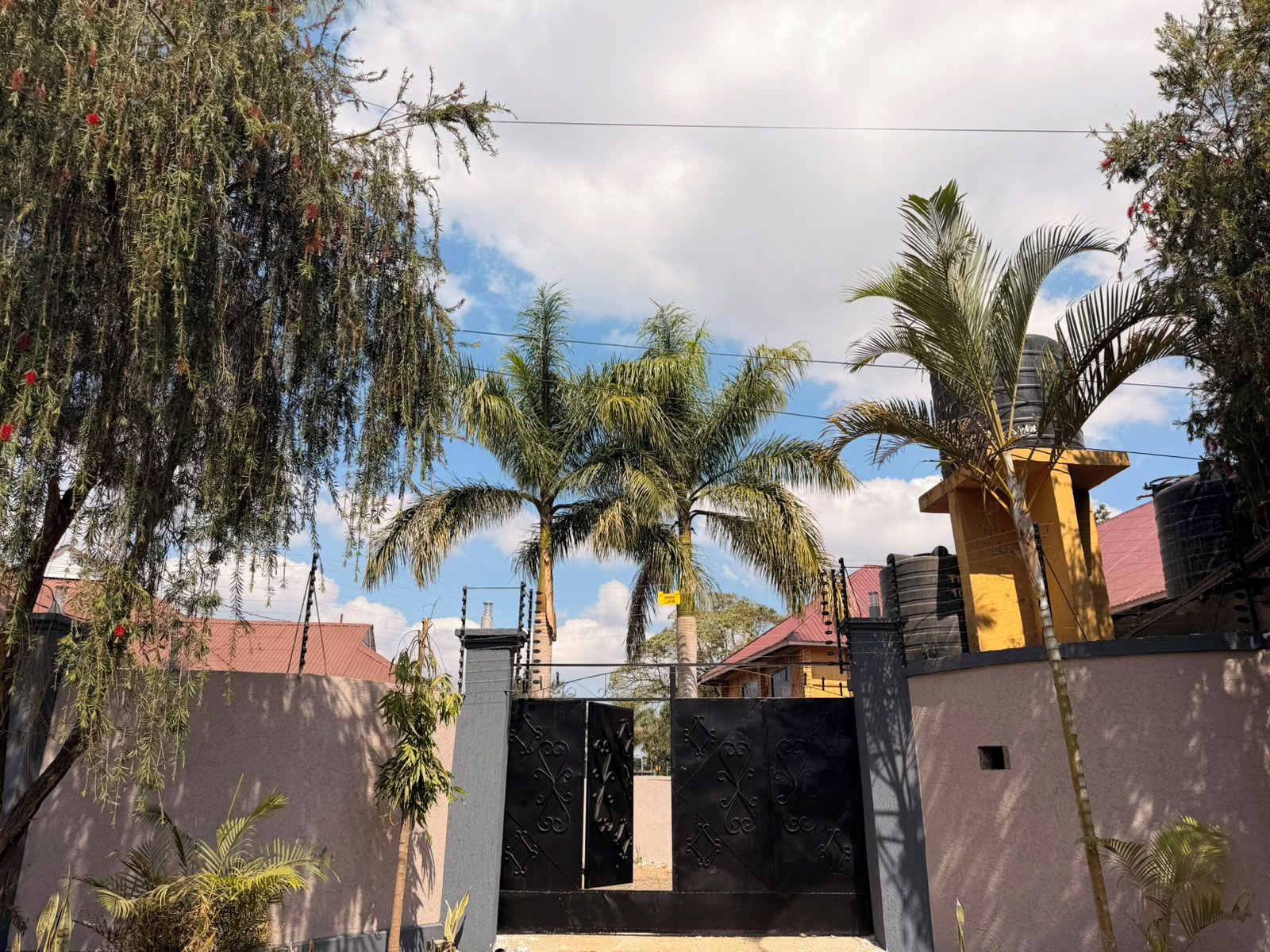A gated residential area with palm trees and a clear sky.