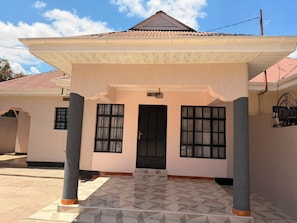 A two-story house with a covered porch, a tiled entrance, and a red-tiled roof.