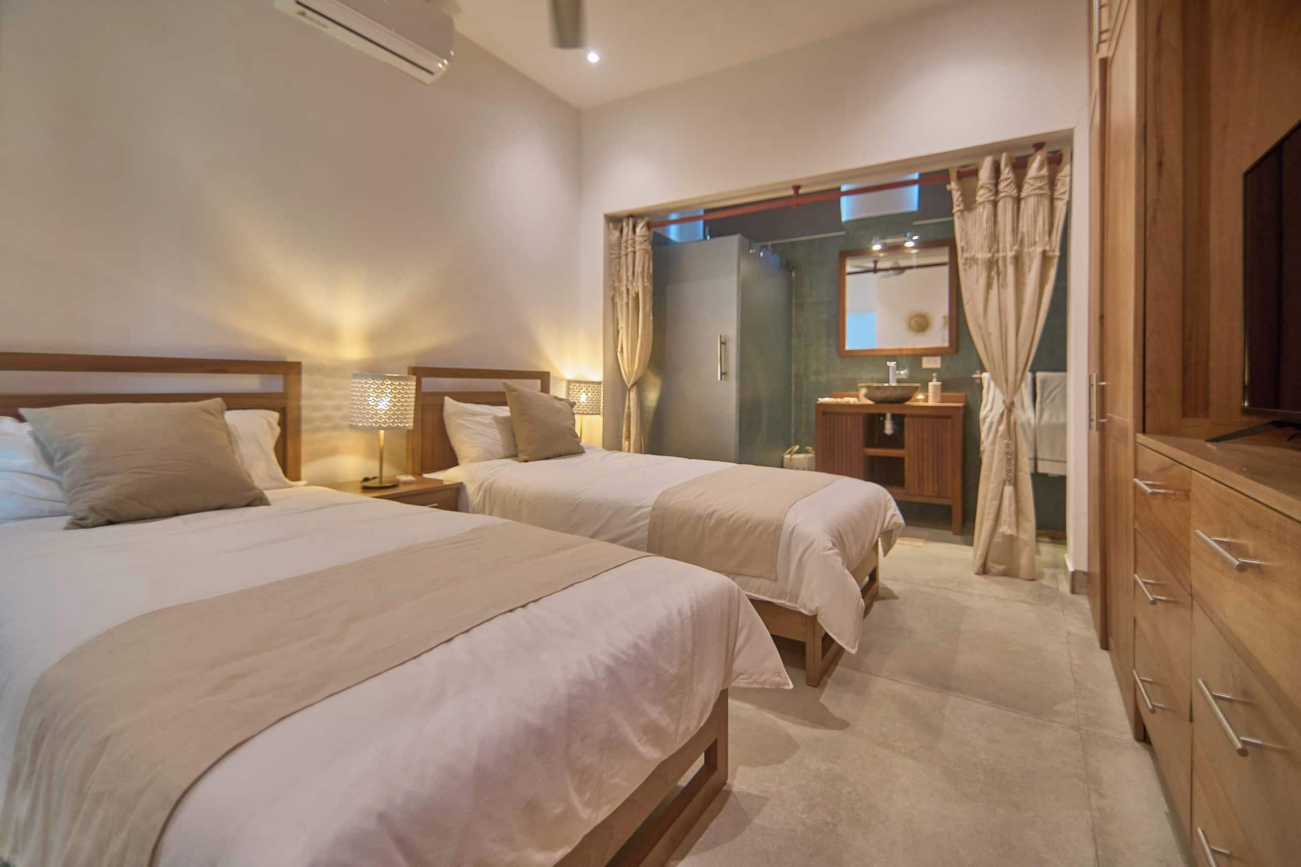 Una habitación de hotel con dos camas, un tocador con espejo y un armario.