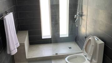 Un baño moderno con ducha, inodoro y un perchero para toallas.