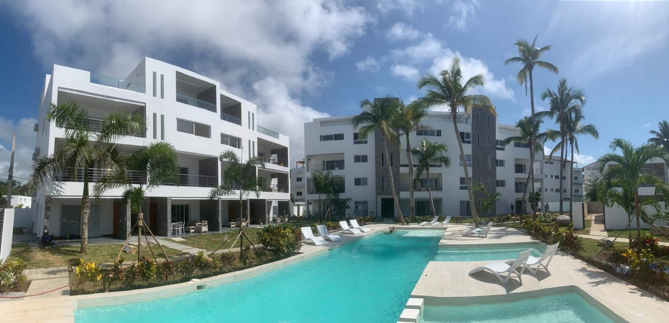Un hôtel moderne doté d’une piscine, de nombreux balcons et de palmiers.