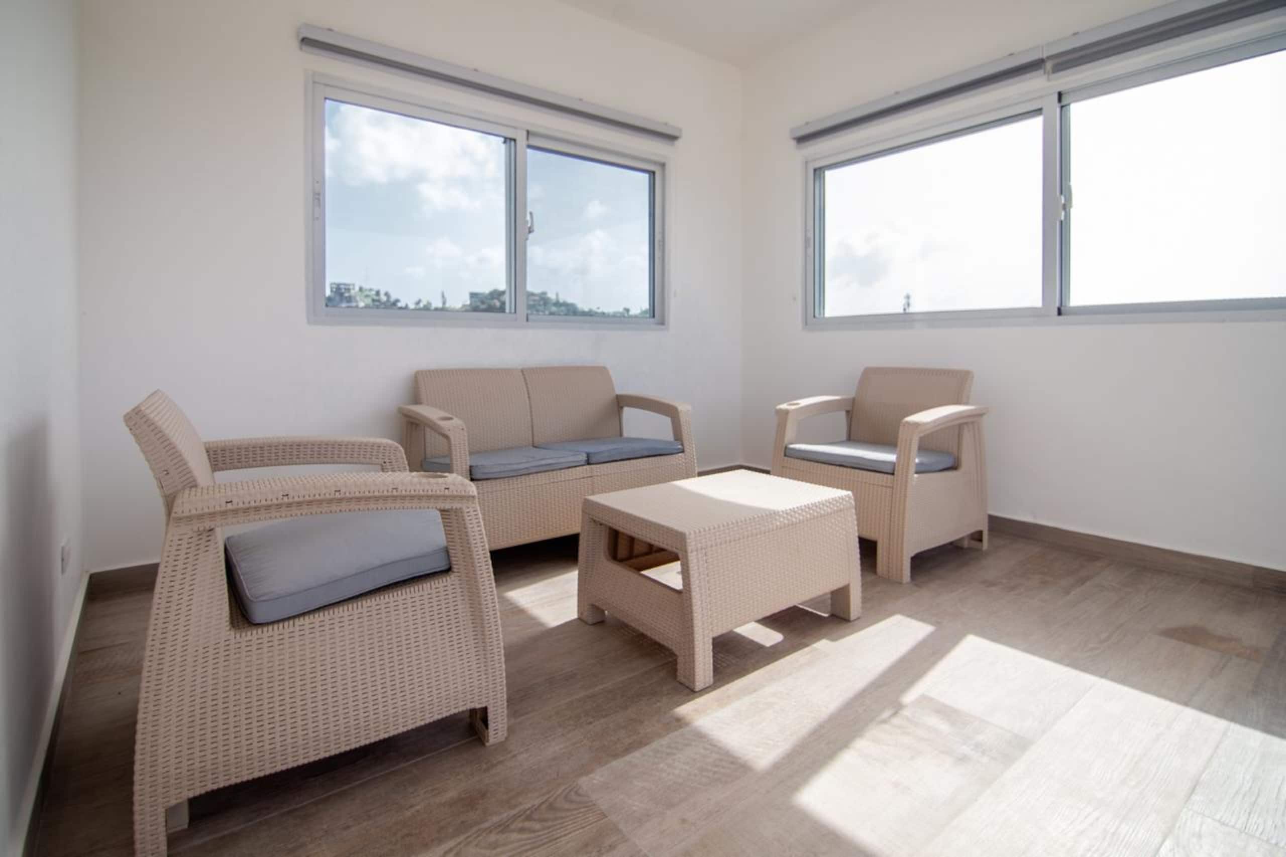 Ein Zimmer mit zwei Sofas, einem Couchtisch, großen Fenstern und Blick auf die Stadt.
