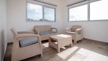 Ein Zimmer mit zwei Sofas, einem Couchtisch, großen Fenstern und Blick auf die Stadt.