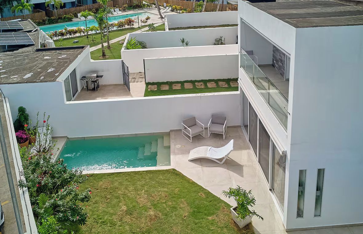 A modern building with a swimming pool, outdoor seating, and a well-maintained garden.