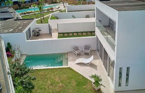 Un edificio moderno con piscina, zona de estar al aire libre y un jardín cuidado.