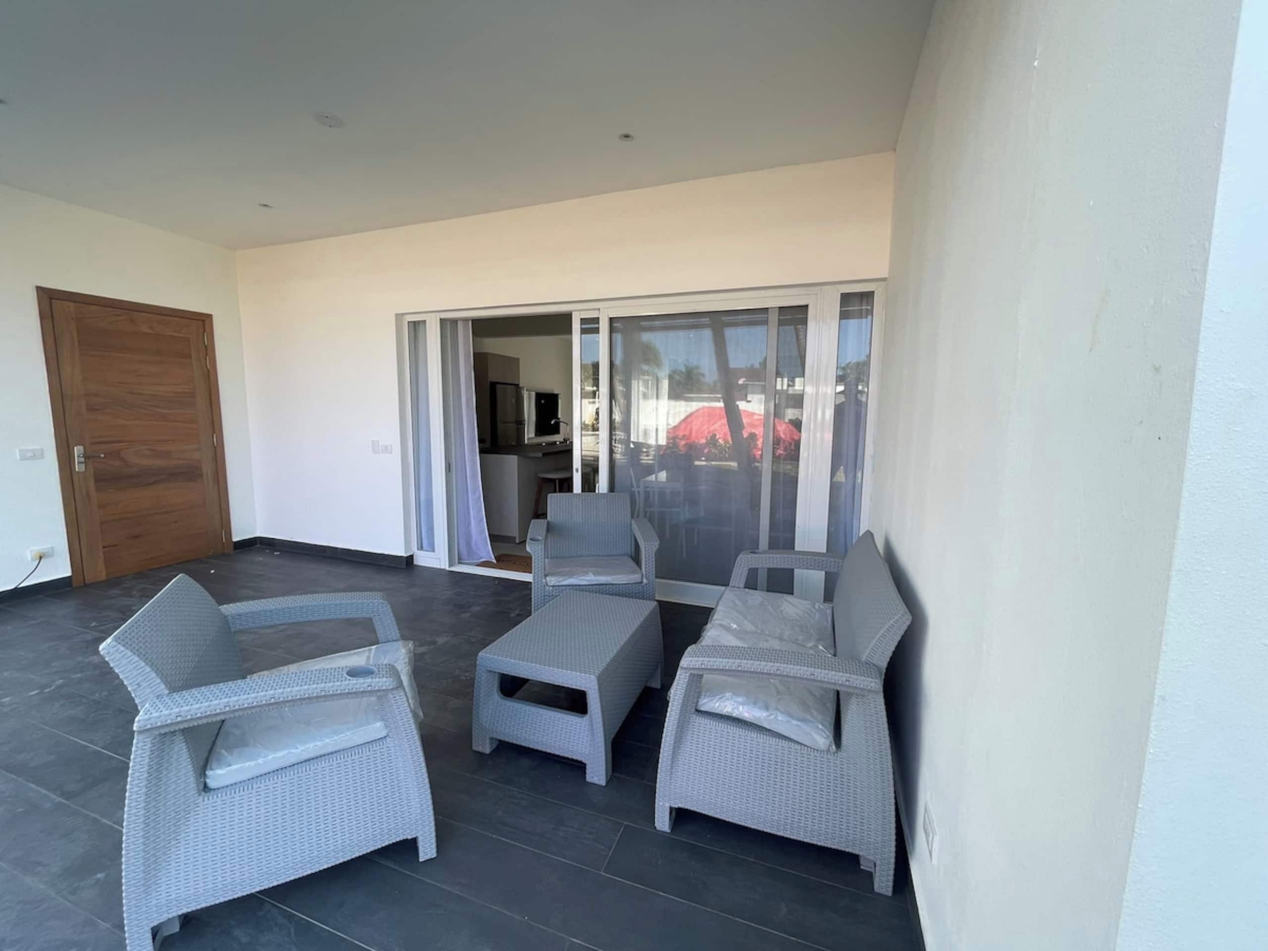 A balcony with wicker furniture and a sliding glass door leading to a dining area.