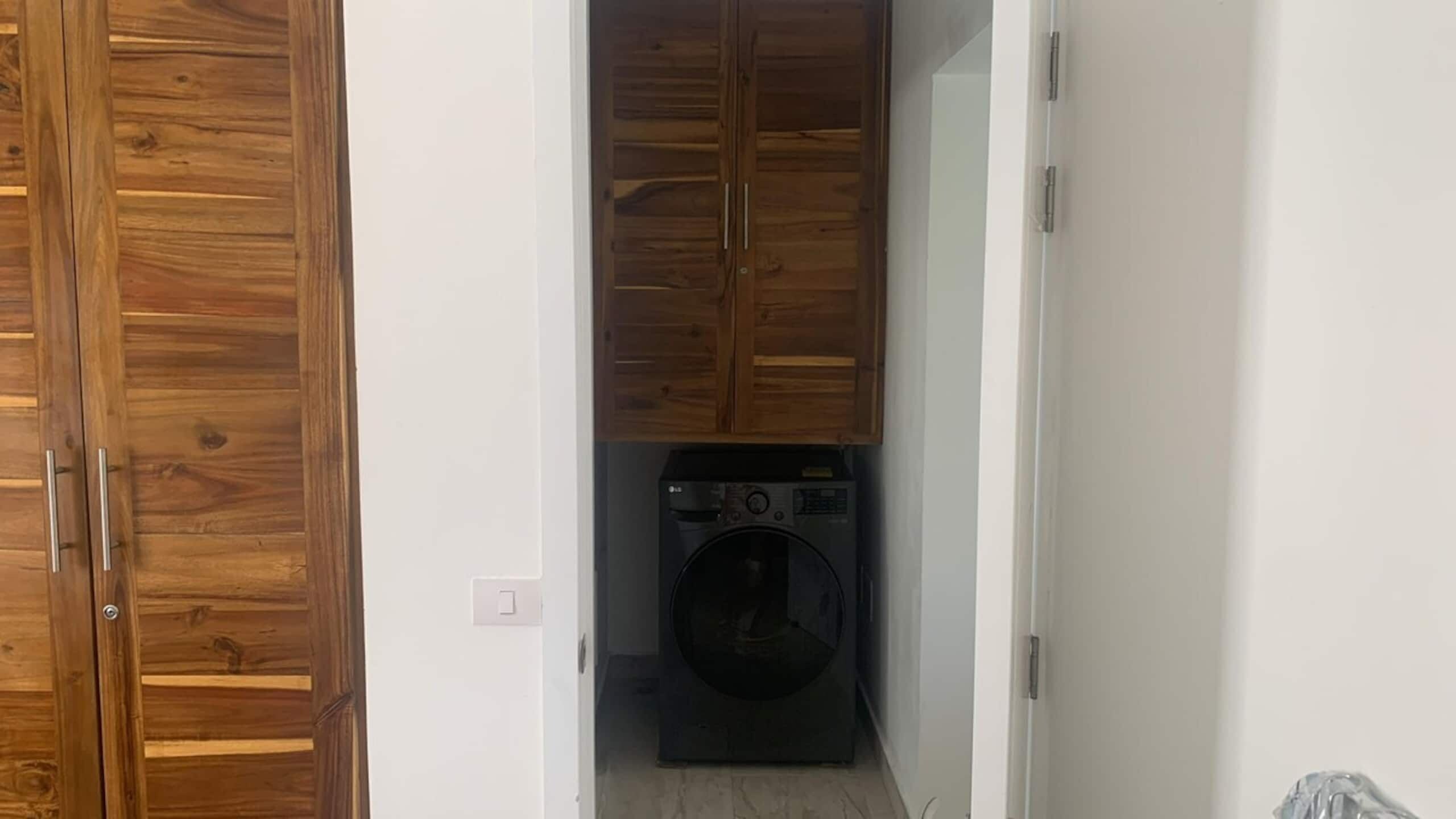 A laundry room with a washing machine and wooden cabinets.
