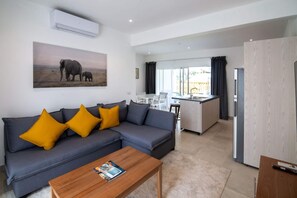 A modern living room with a grey sofa, wooden coffee table, and a painting of elephants. - Case Damare Coralstone 3 (Las terrenas)