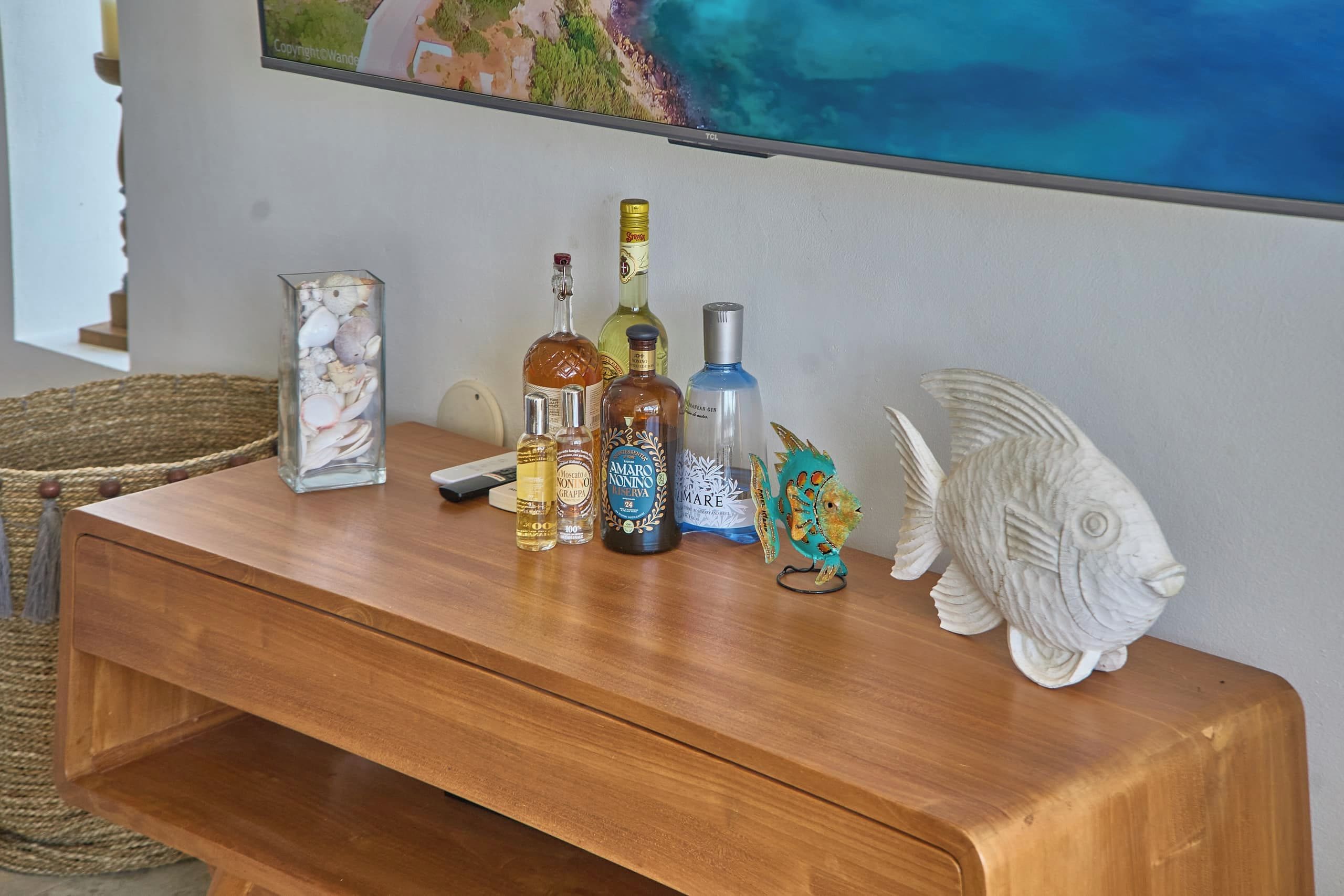 Una mesa de madera con varias botellas y una escultura decorativa de un pez.