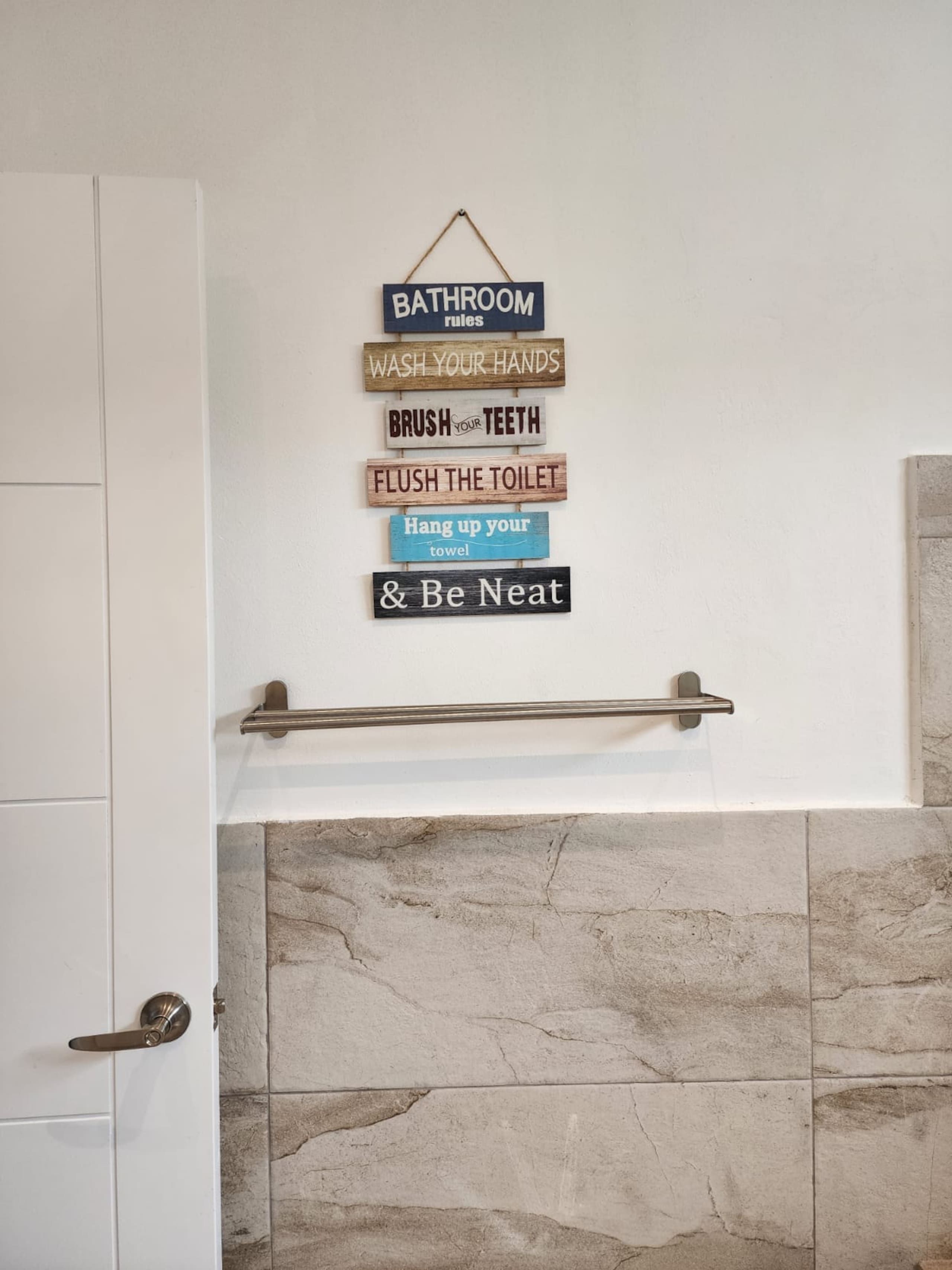 A bathroom with a towel rack and a sign with bathroom rules.