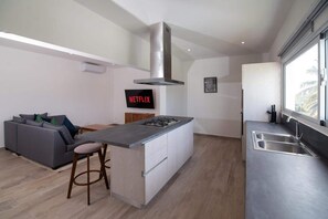 A modern kitchen with a central island, a built-in stove, and a stainless steel sink. - Case Damare Coralstone 3 (Las terrenas)