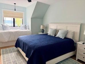 A bedroom with a bed, bedside tables, and a window with a view.